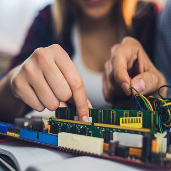 Hands touch computer chips and wires.