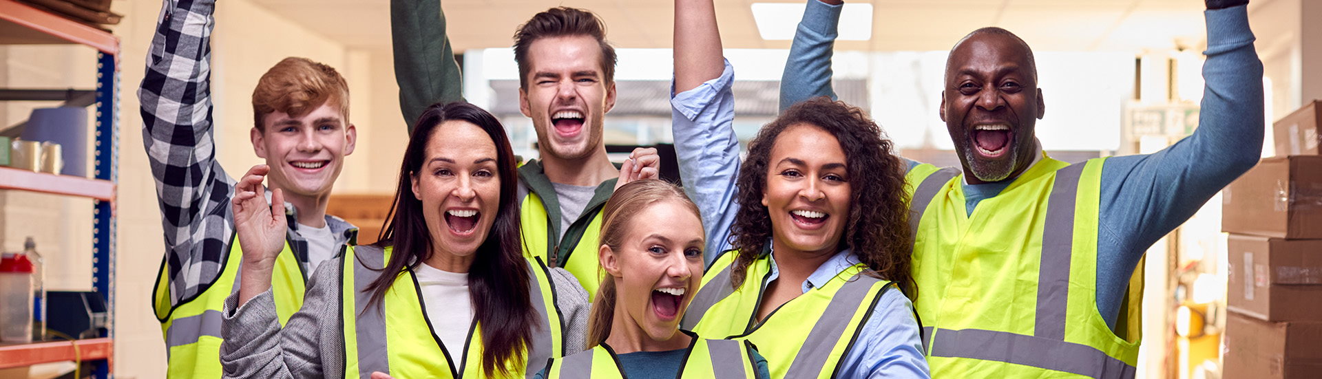 procurri-warehouse-careers Drei Männer und drei Frauen in gelben Warnwesten feiern und lächeln in die Kamera.